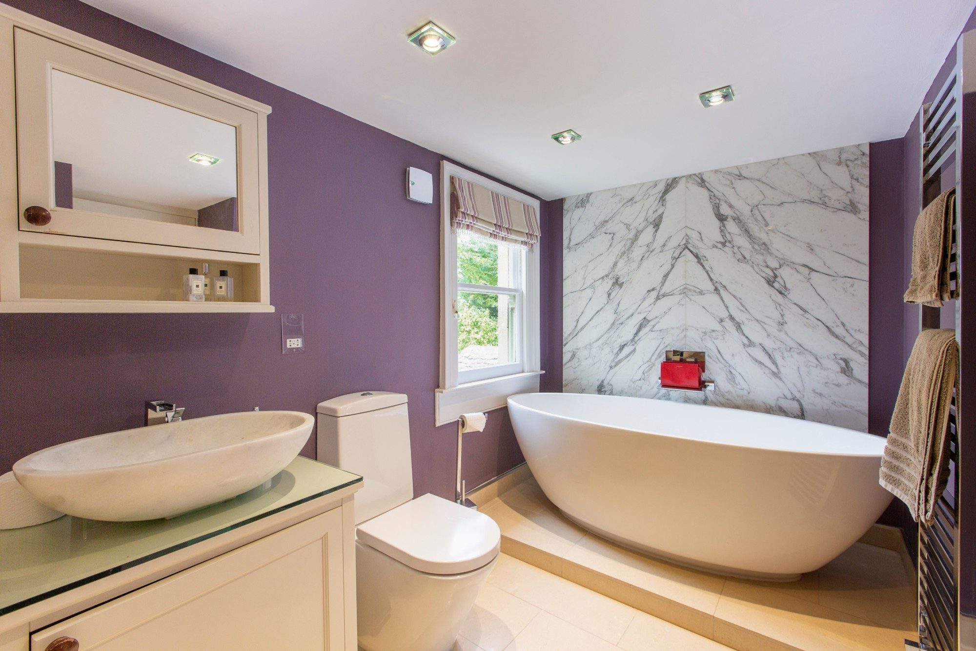 Bathroom with a freestanding oval bath set against a bookmatched marble wall