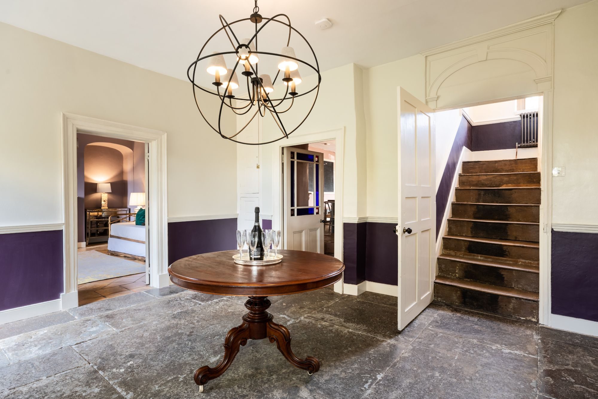 Entrance hall with original flagstone floor, orb chandelier and aubergine dado panelling